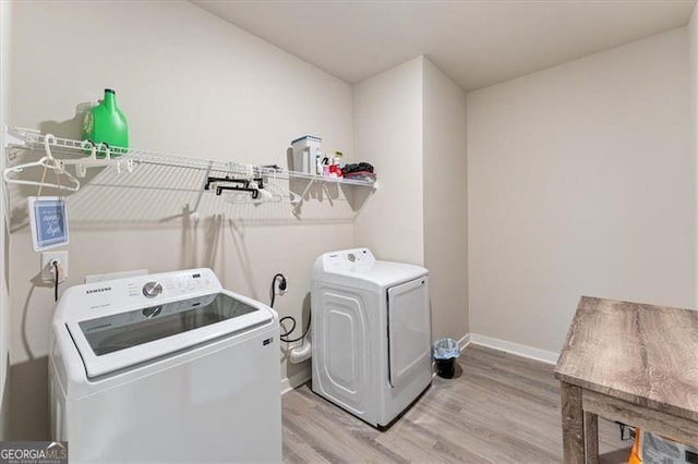 laundry room with laundry area, baseboards, light wood finished floors, and washing machine and clothes dryer