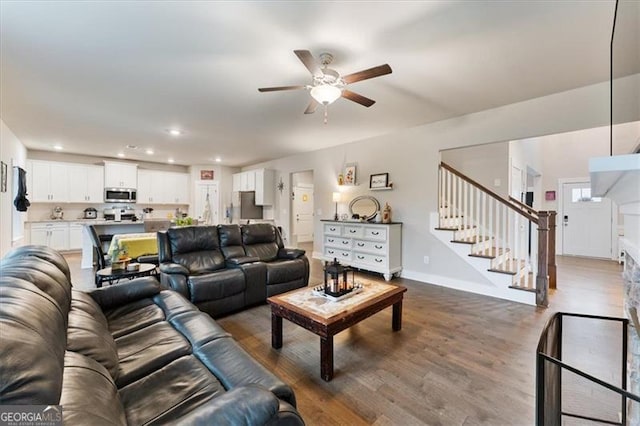 living area with ceiling fan, recessed lighting, wood finished floors, baseboards, and stairs