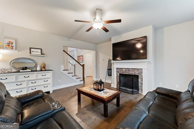 living room with baseboards, stairway, dark wood-style flooring, and a stone fireplace