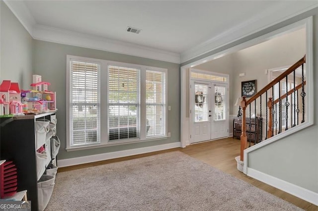 entrance foyer with wood finished floors, visible vents, baseboards, stairs, and crown molding