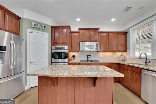 kitchen with a kitchen breakfast bar, a center island, stainless steel appliances, crown molding, and a sink