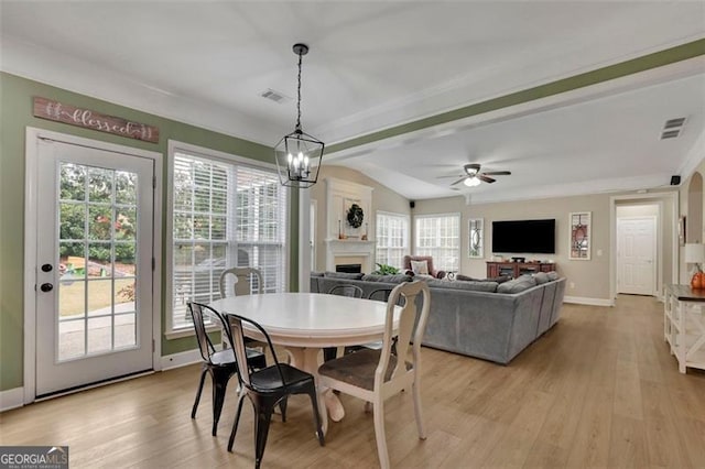 dining area featuring light wood-style floors, visible vents, and a fireplace