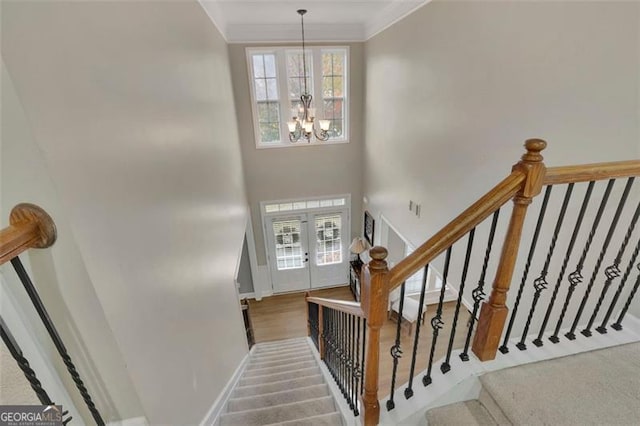 staircase featuring baseboards, a towering ceiling, crown molding, french doors, and a chandelier