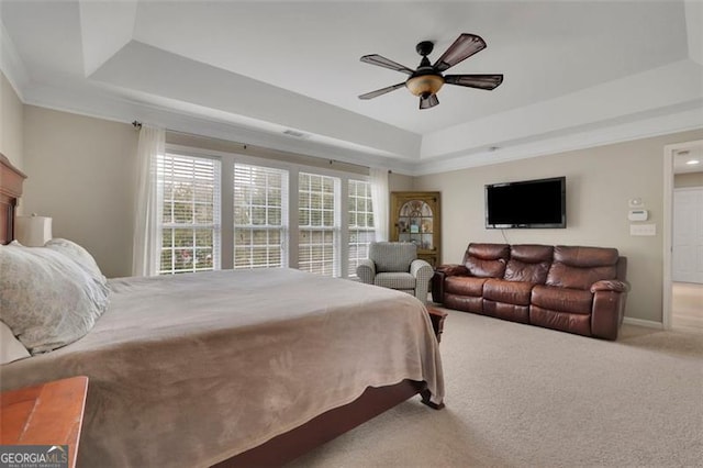 bedroom with carpet floors, a raised ceiling, baseboards, and a ceiling fan