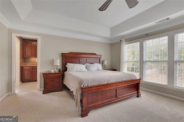 bedroom featuring a tray ceiling, visible vents, light carpet, and baseboards