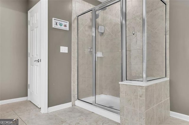 full bath with a stall shower, baseboards, and tile patterned floors