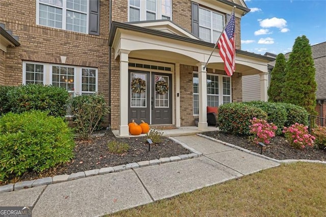 property entrance featuring a porch and brick siding