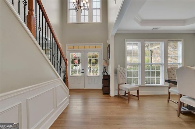 foyer featuring light wood-type flooring, an inviting chandelier, stairs, and a wealth of natural light