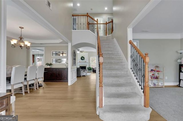 stairway with plenty of natural light, crown molding, baseboards, and wood finished floors