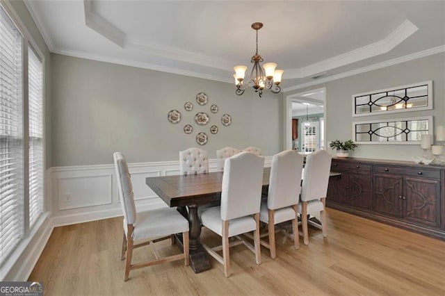 dining area featuring a tray ceiling, a wealth of natural light, and an inviting chandelier