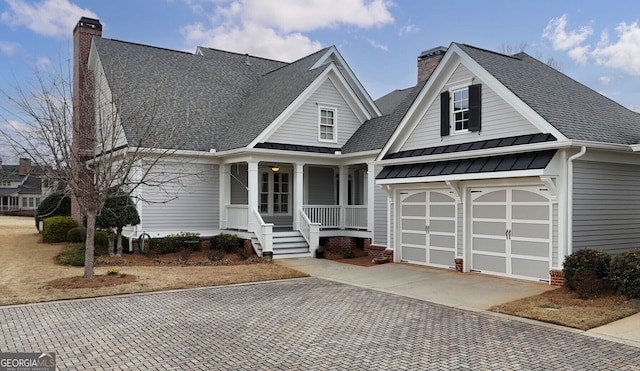 view of front facade with decorative driveway, a standing seam roof, and a chimney