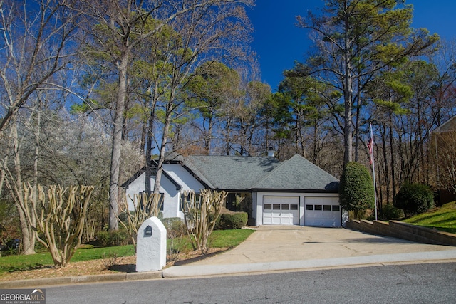 ranch-style house featuring concrete driveway, a garage, and roof with shingles