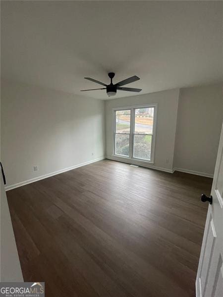 empty room featuring baseboards, a ceiling fan, and dark wood-type flooring