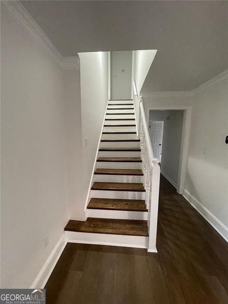 stairway featuring crown molding, baseboards, and wood finished floors