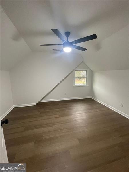 additional living space featuring dark wood-style floors, baseboards, visible vents, and vaulted ceiling