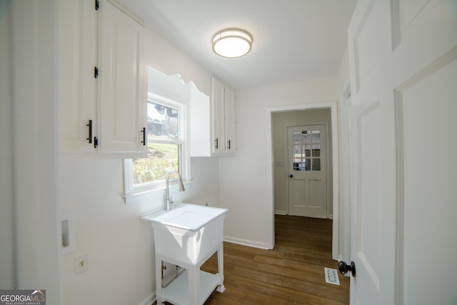 laundry area with visible vents, cabinet space, baseboards, and dark wood-style flooring