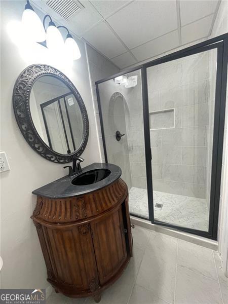 bathroom featuring a stall shower, visible vents, a paneled ceiling, and vanity