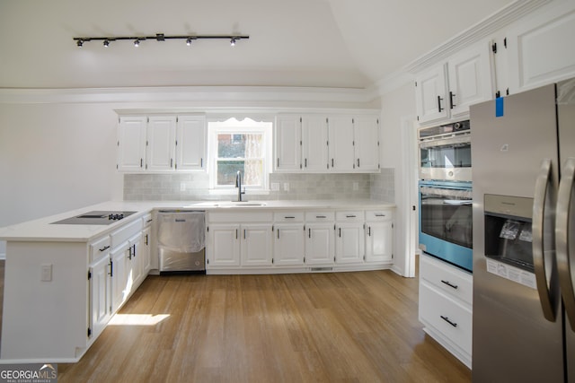 kitchen with a sink, stainless steel appliances, light countertops, white cabinetry, and light wood-type flooring