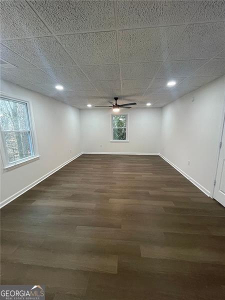 interior space featuring dark wood-style floors, a paneled ceiling, recessed lighting, a ceiling fan, and baseboards