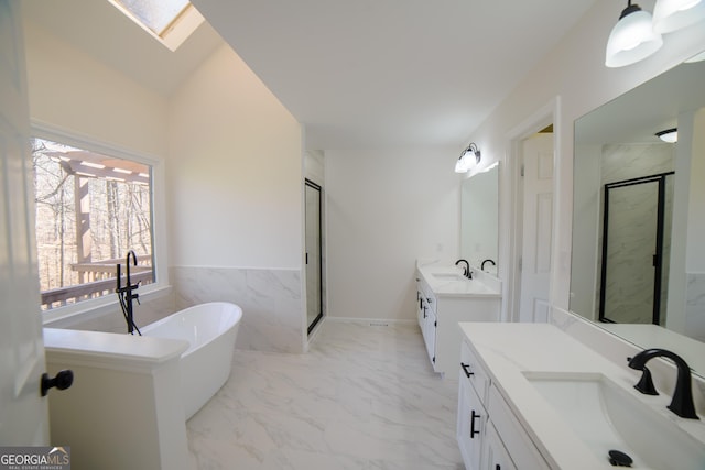 bathroom featuring a sink, marble finish floor, a stall shower, and a skylight