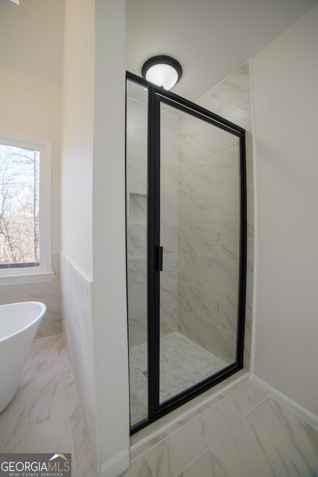 full bath featuring wainscoting, marble finish floor, a stall shower, and a freestanding tub