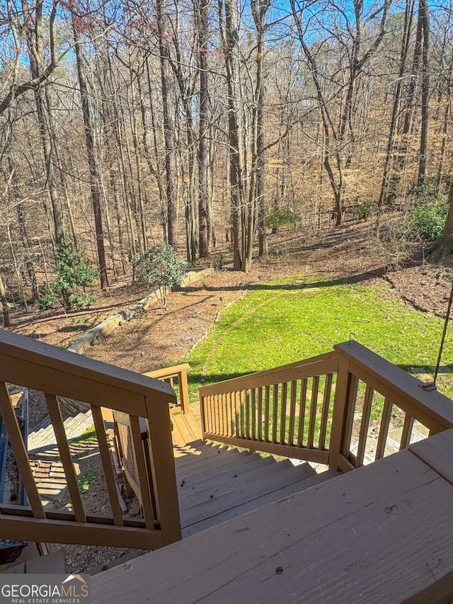 wooden terrace with a lawn and a wooded view