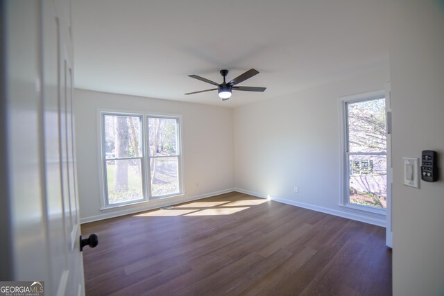 unfurnished room featuring dark wood finished floors, ceiling fan, and baseboards