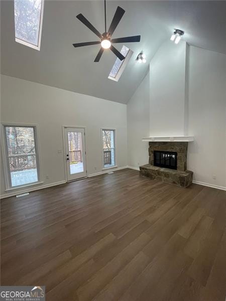 unfurnished living room featuring a ceiling fan, dark wood-type flooring, a stone fireplace, high vaulted ceiling, and baseboards