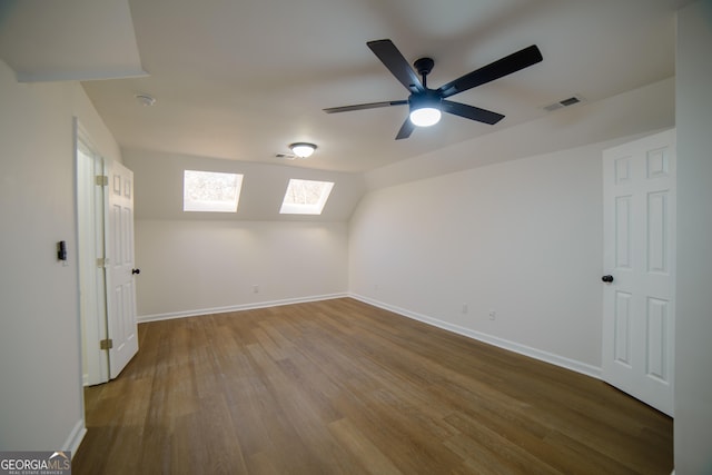 interior space featuring lofted ceiling, wood finished floors, visible vents, and baseboards