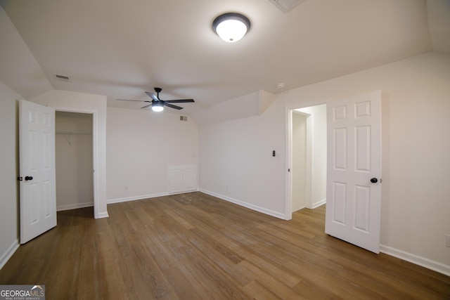 unfurnished bedroom with visible vents, wood finished floors, a closet, baseboards, and vaulted ceiling