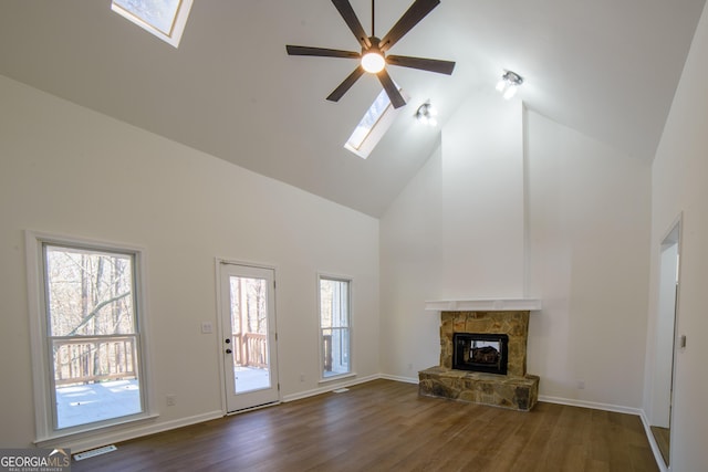 unfurnished living room with dark wood-type flooring, a skylight, a fireplace, and visible vents