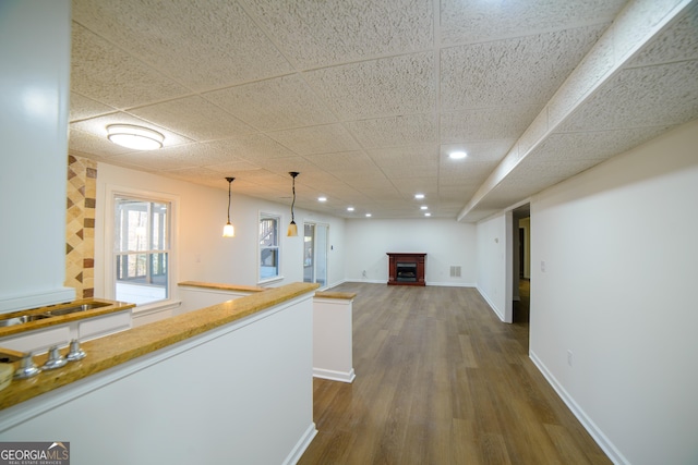 hall with visible vents, a drop ceiling, dark wood finished floors, recessed lighting, and baseboards