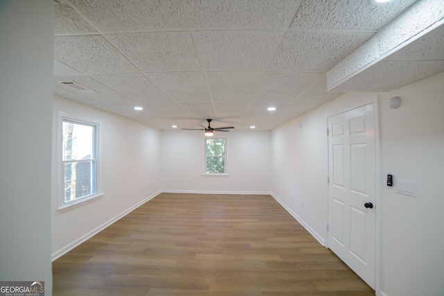 spare room featuring wood finished floors, baseboards, a wealth of natural light, and a paneled ceiling