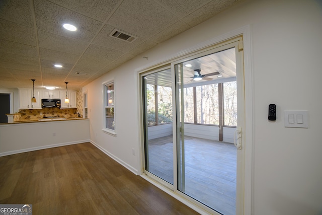 doorway with visible vents, baseboards, a drop ceiling, recessed lighting, and dark wood-style floors