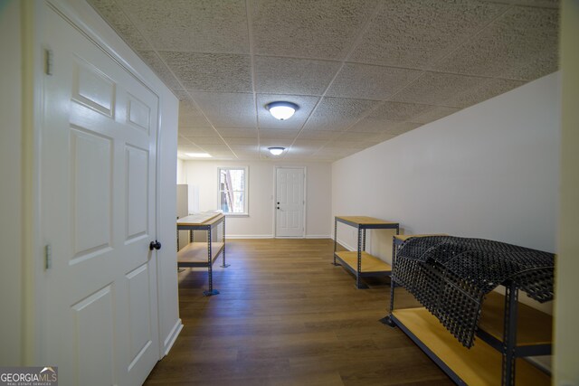 interior space featuring baseboards, a paneled ceiling, and wood finished floors