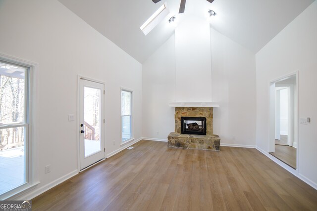 unfurnished living room featuring a fireplace, high vaulted ceiling, baseboards, and wood finished floors