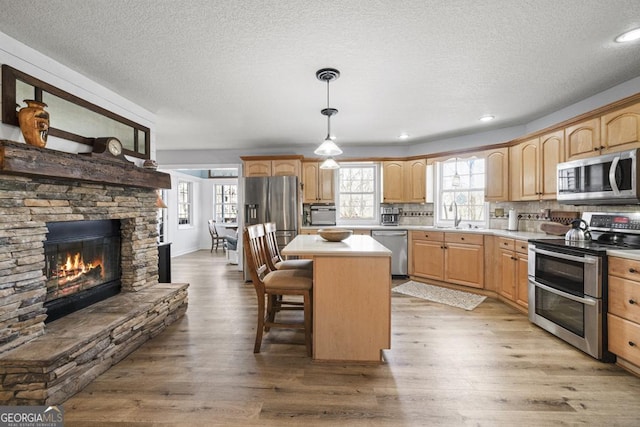 kitchen with stainless steel appliances, light countertops, a kitchen island, and light wood-style flooring