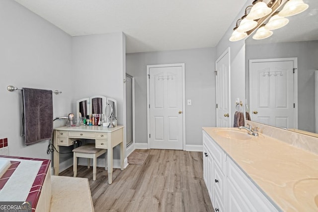 bathroom with double vanity, wood finished floors, a sink, and baseboards