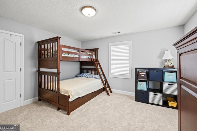 bedroom featuring a textured ceiling, carpet flooring, visible vents, and baseboards