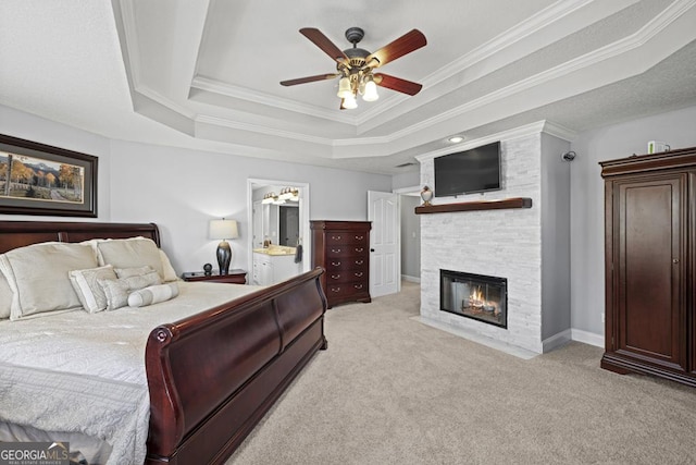 bedroom with carpet, ornamental molding, a raised ceiling, and a stone fireplace