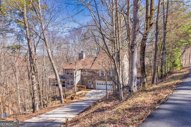 view of front facade featuring driveway, a garage, and a chimney