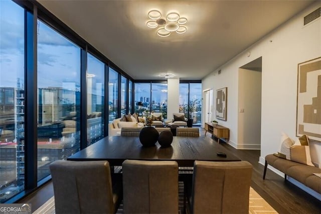 interior space with baseboards, wood finished floors, visible vents, and floor to ceiling windows