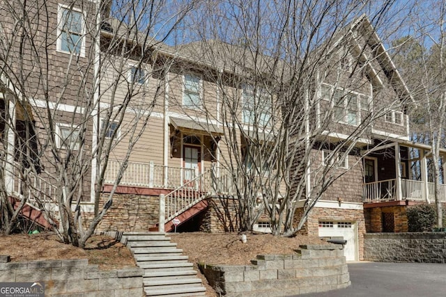 townhome / multi-family property featuring aphalt driveway, stairway, and an attached garage