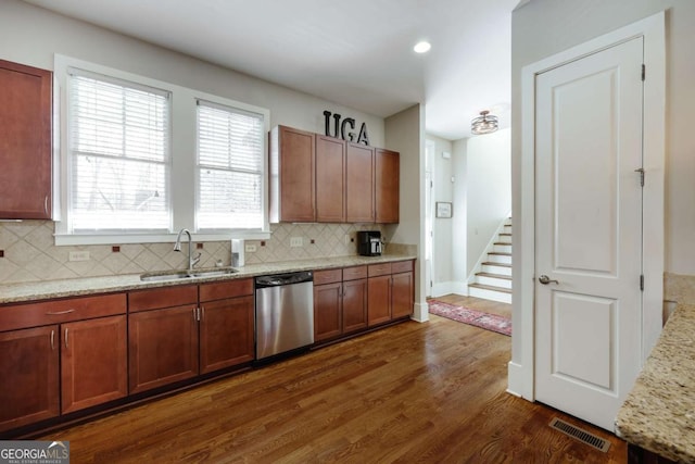 kitchen featuring a sink, visible vents, stainless steel dishwasher, backsplash, and dark wood-style floors