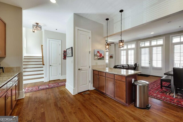 310 Research Dr Unit 303, Athens, GA 30605 - kitchen with brown cabinetry, a peninsula, dark wood-style flooring, pendant lighting, and light stone countertops