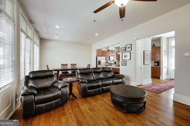 living room featuring a ceiling fan, recessed lighting, baseboards, and light wood finished floors