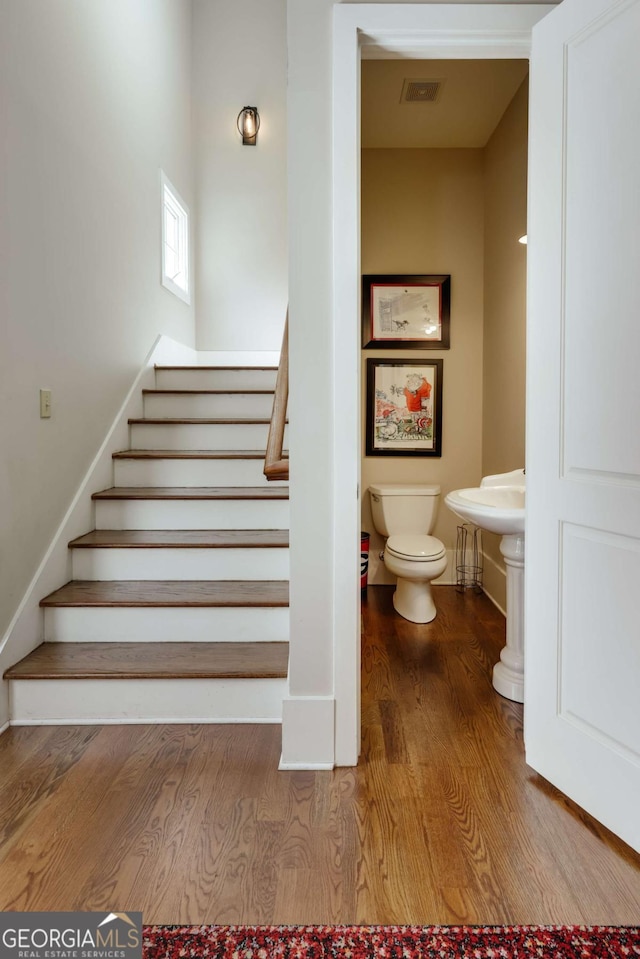 stairs with wood finished floors and visible vents