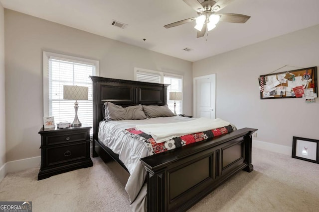 bedroom featuring light carpet, baseboards, visible vents, and a ceiling fan