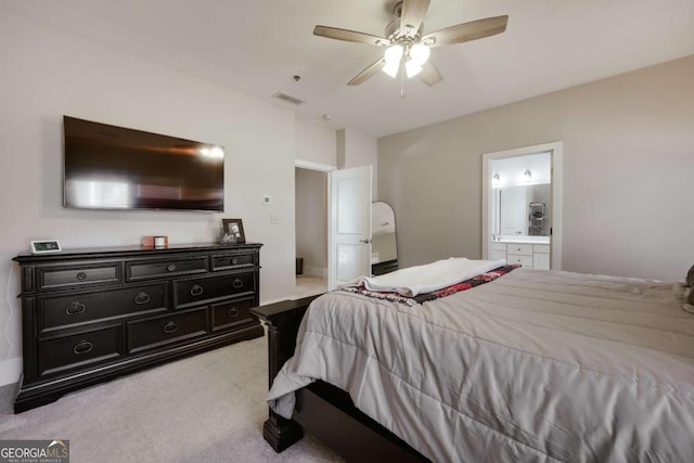 bedroom with a ceiling fan, light colored carpet, visible vents, and ensuite bathroom