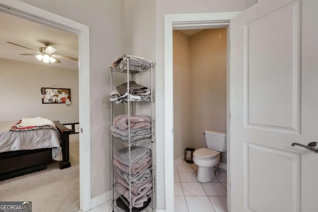 ensuite bathroom with ceiling fan, tile patterned flooring, toilet, baseboards, and ensuite bath